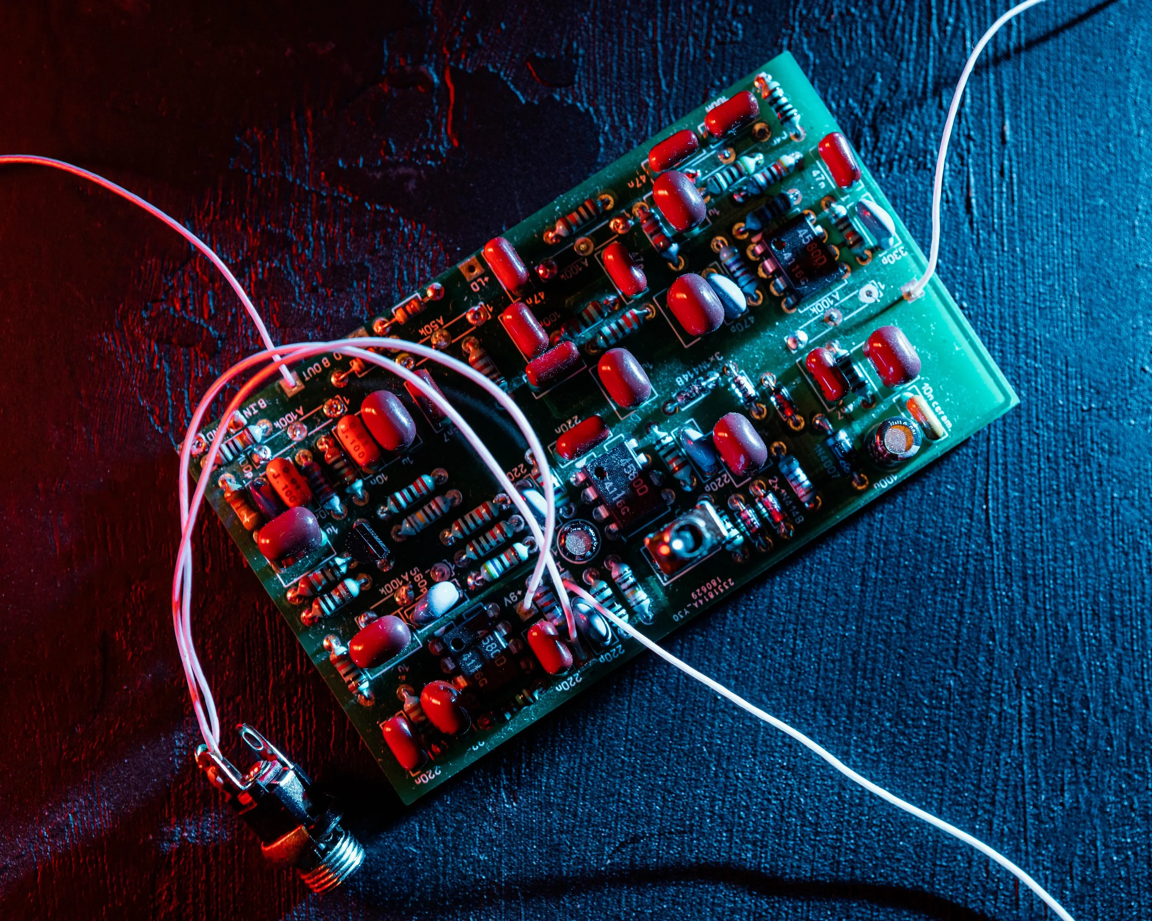 12v rechargeable battery and PCB boards on dark matte surface with neon green light